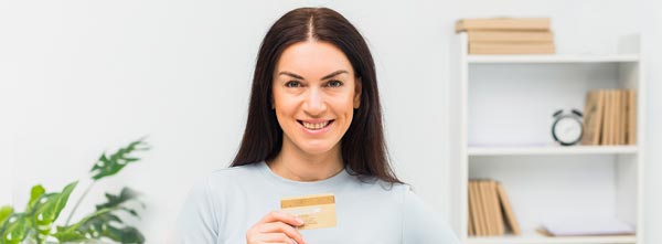 quanto ganha um terapeuta holístico? mulher sorrindo satisfeita com cartão de crédito