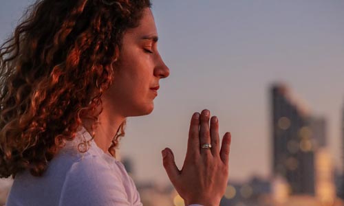 Mulher em Namaste praticando Svadhyaya: a busca por autoconhecimento no Yoga