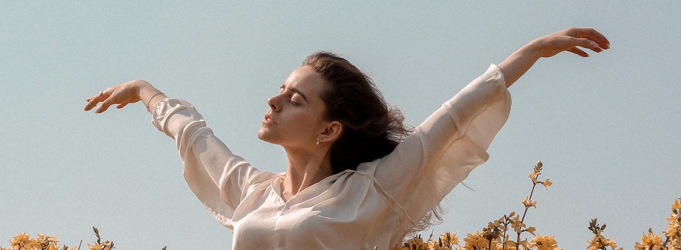 como desenvolver inteligência emocional: mulher em plenitude de braços abertos em campo